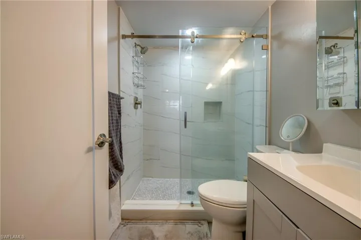 Bathroom featuring vanity and a marble finish shower