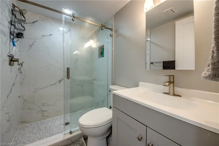 Full bath with vanity and a marble finish shower