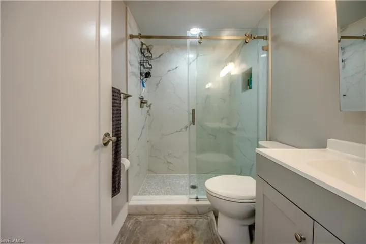 Bathroom featuring vanity and a marble finish shower