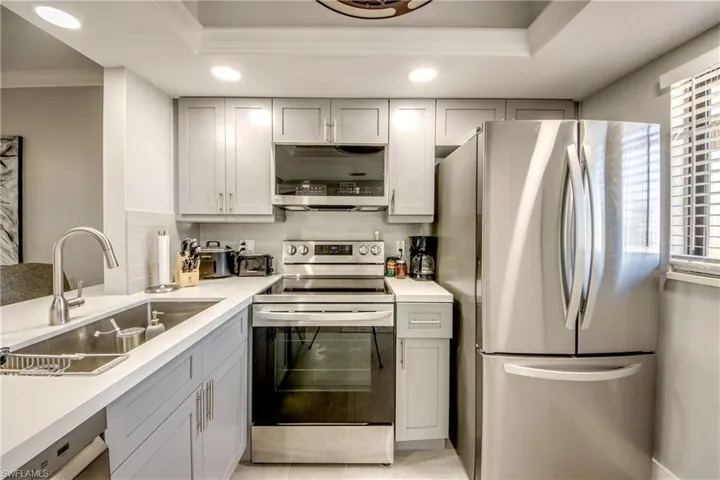 Kitchen featuring stainless steel appliances, gray cabinetry, tasteful backsplash, recessed lighting, and crown molding