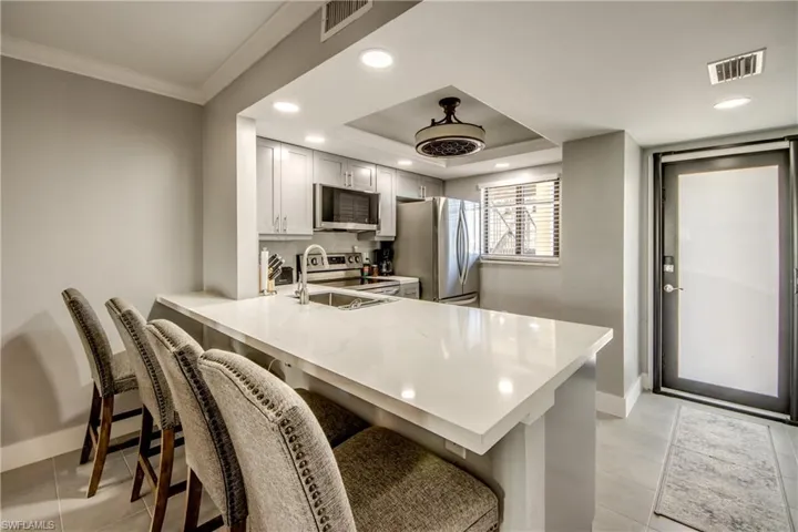 Kitchen with a peninsula, recessed lighting, a kitchen bar, appliances with stainless steel finishes, and light tile patterned floors
