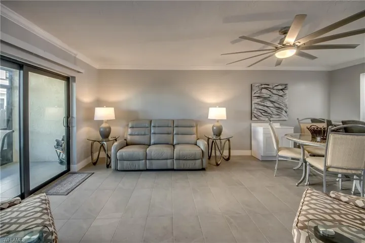 Living area featuring ornamental molding, a ceiling fan, and healthy amount of natural light