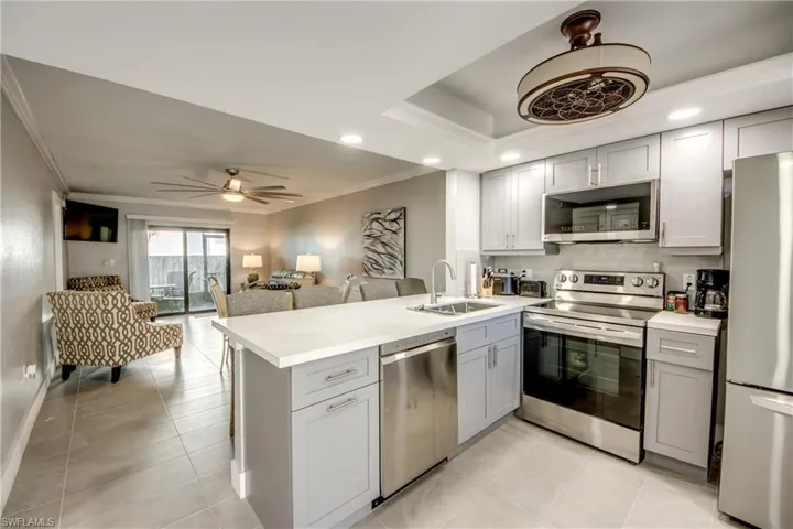 Kitchen featuring appliances with stainless steel finishes, light countertops, a peninsula, gray cabinets, and crown molding