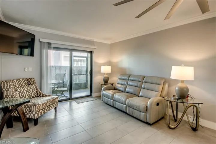Tiled living room with crown molding and ceiling fan