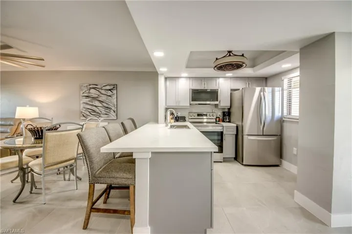 Kitchen with a peninsula, stainless steel appliances, a breakfast bar area, open floor plan, and gray cabinetry