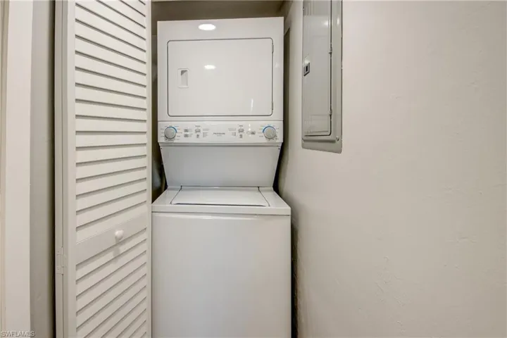 Washroom featuring electric panel and stacked washing machine and dryer