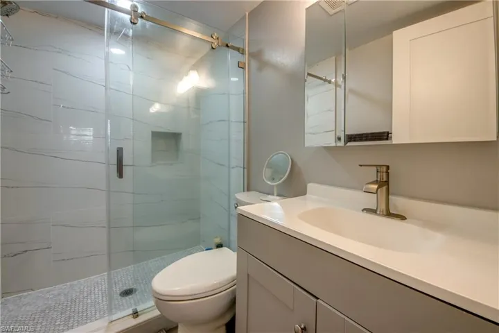 Full bathroom featuring a marble finish shower and vanity