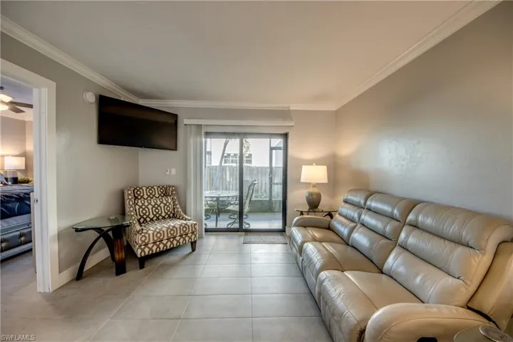 Tiled living area featuring ornamental molding and a ceiling fan