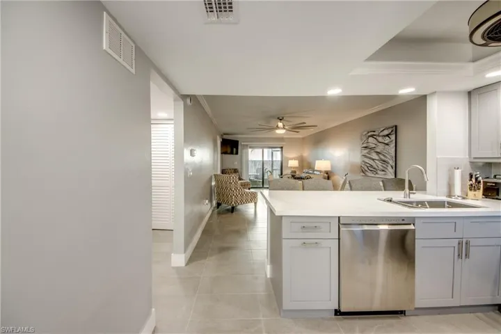 Kitchen with a peninsula, stainless steel dishwasher, gray cabinetry, crown molding, and open floor plan
