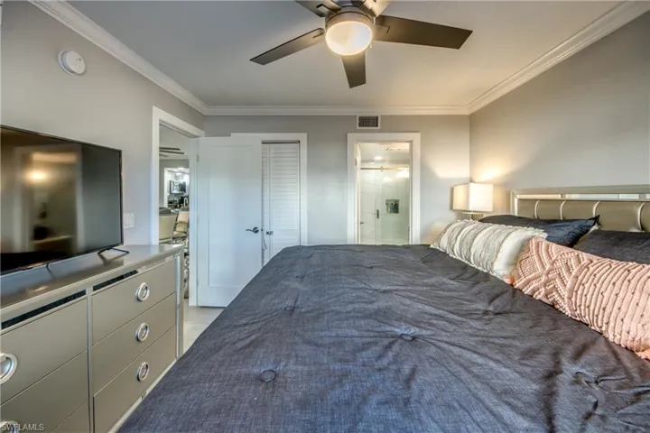 Bedroom with crown molding, a ceiling fan, a closet, and ensuite bathroom