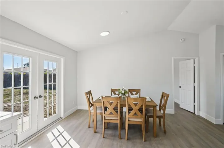 Dining space with lofted ceiling, wood finished floors, and french doors