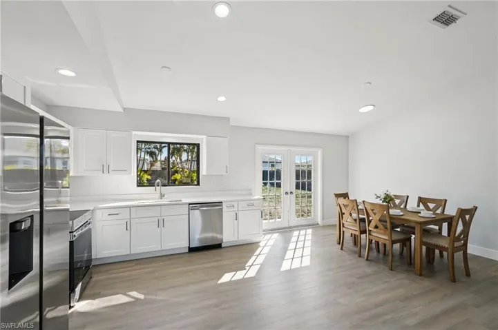 Kitchen featuring stainless steel appliances, white cabinets, light wood-style floors, recessed lighting, and french doors