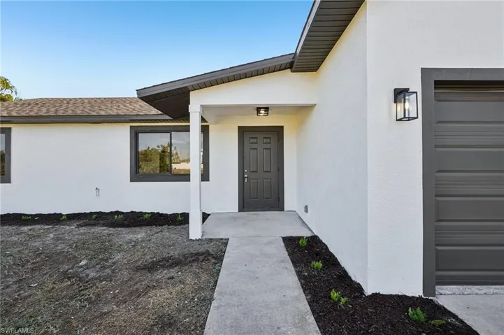 Entrance to property with stucco siding, roof with shingles, and a garage