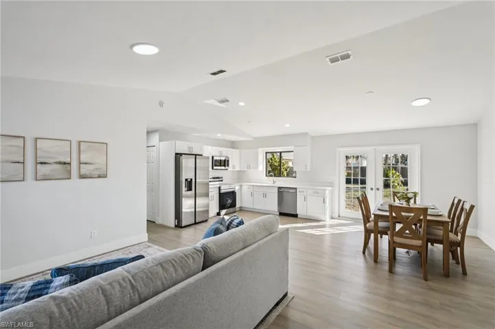 Living area featuring french doors, light wood finished floors, lofted ceiling, and recessed lighting