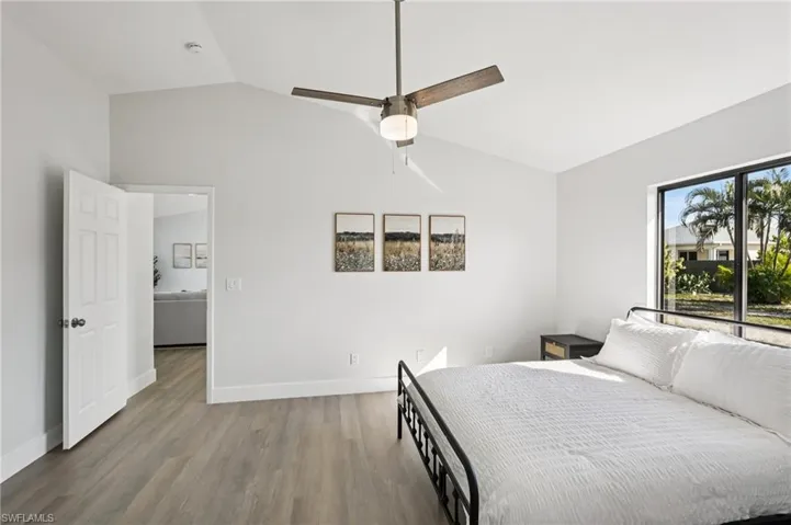 Bedroom with vaulted ceiling, wood finished floors, and a ceiling fan