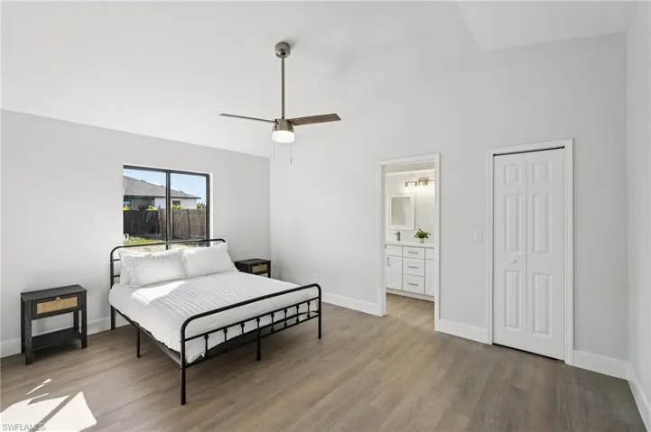 Bedroom with vaulted ceiling, light wood finished floors, a closet, a ceiling fan, and ensuite bath