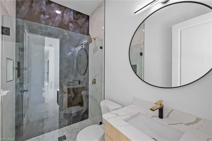 Bathroom featuring a shower with door, vanity, and toilet