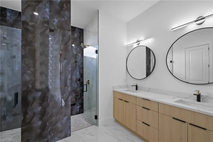 Bathroom featuring a shower with shower door and vanity