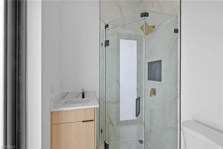 Bathroom featuring toilet, an enclosed shower, and vanity