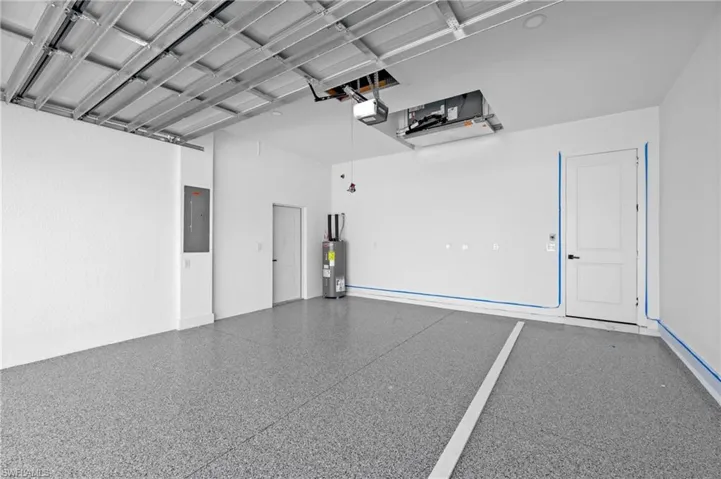 Garage with electric panel, water heater, and a garage door opener
