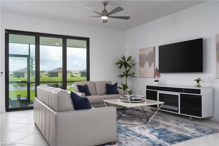Living room with a ceiling fan, light tile patterned floors, and a residential view