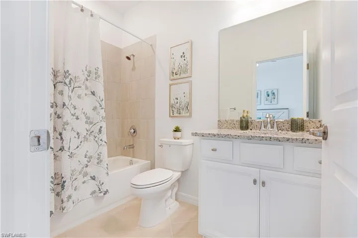 Full bath featuring vanity, shower / tub combo with curtain, and light tile patterned flooring