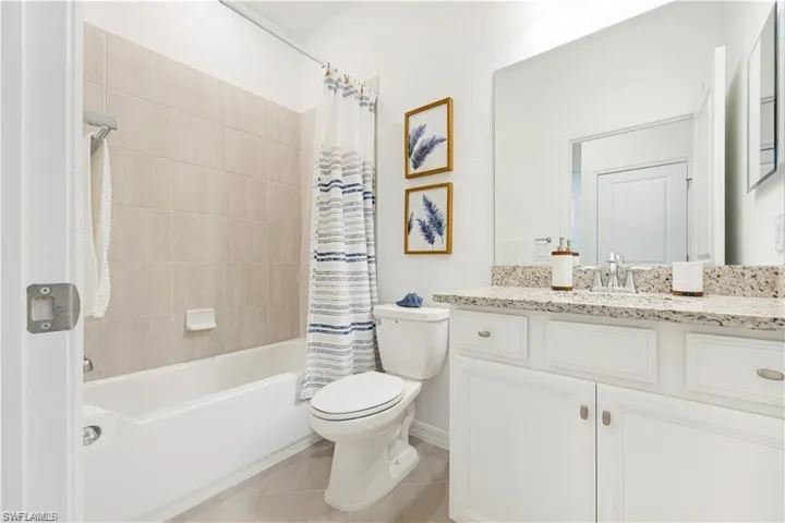 Full bath featuring vanity, shower / bath combo with shower curtain, and light tile patterned floors