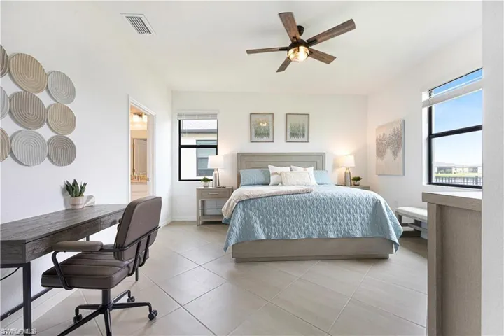 Bedroom with ceiling fan, light tile patterned floors, and ensuite bath