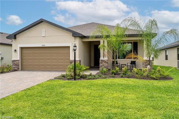 View of front of house with stone siding, stucco siding, an attached garage, and driveway