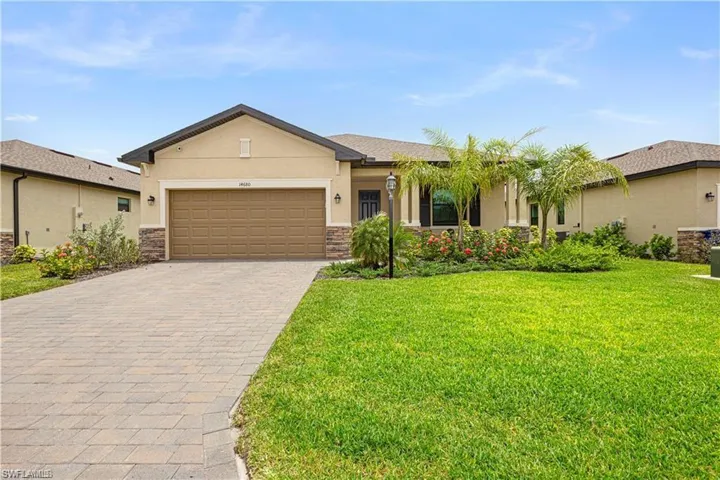Ranch-style home with stucco siding, an attached garage, decorative driveway, and stone siding