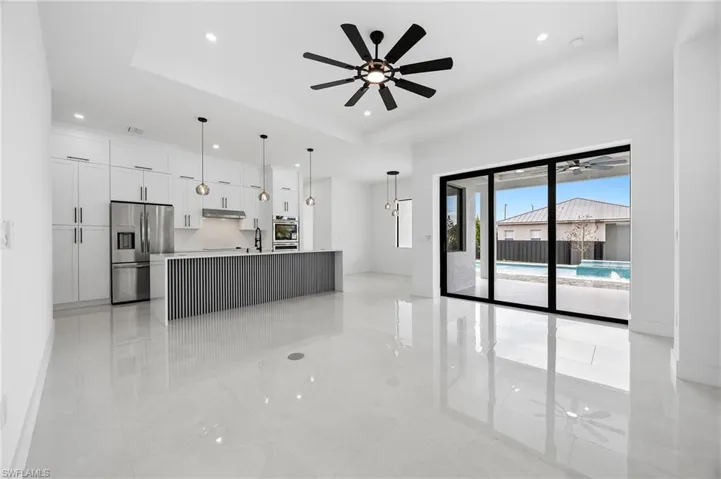 Kitchen with ceiling fan, white cabinetry, a raised ceiling, and stainless steel appliances