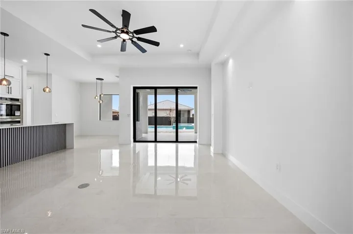 Unfurnished living room with a ceiling fan, a raised ceiling, and recessed lighting