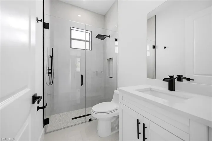 Full bathroom featuring a stall shower, vanity, and light tile patterned floors