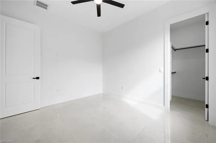 Unfurnished bedroom featuring a spacious closet and ceiling fan