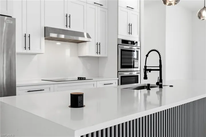 Kitchen featuring white cabinets, light stone countertops, and stainless steel appliances
