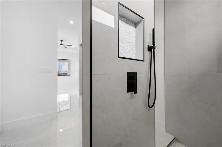 Bathroom with a marble finish shower and recessed lighting