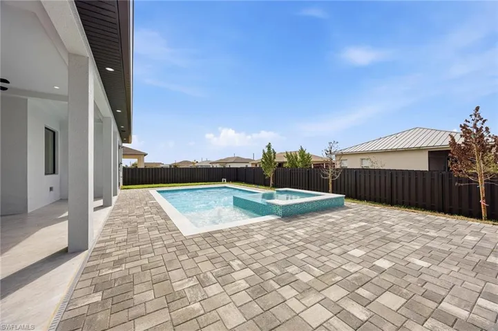 Integrated pool / hot tub with a patio and a fenced backyard