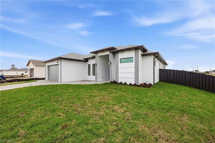 Prairie-style home with stucco siding, an attached garage, driveway, and a patio area