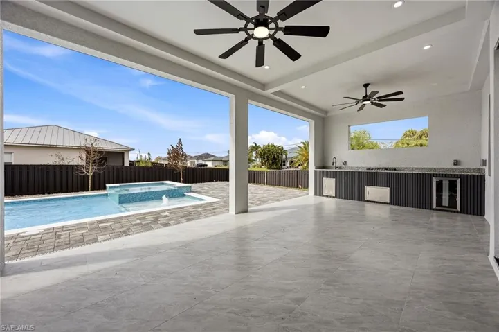 Fenced backyard featuring ceiling fan, a patio area, and a pool with connected hot tub