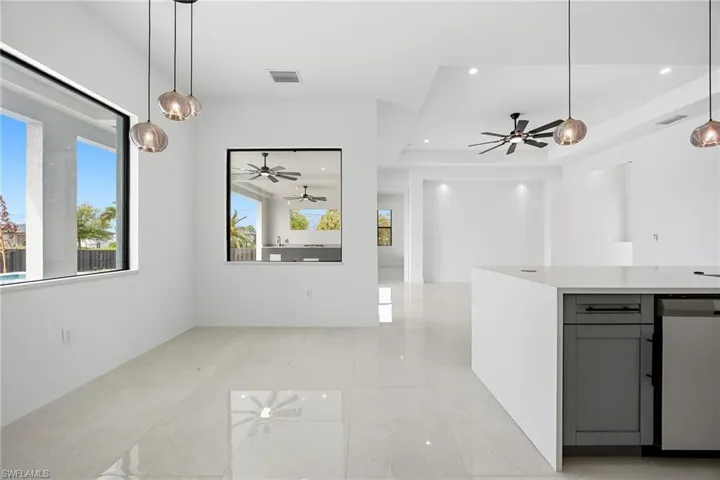 Kitchen with hanging light fixtures, ceiling fan, and a raised ceiling