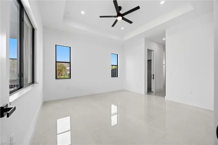 Empty room featuring a ceiling fan, recessed lighting, and a tray ceiling