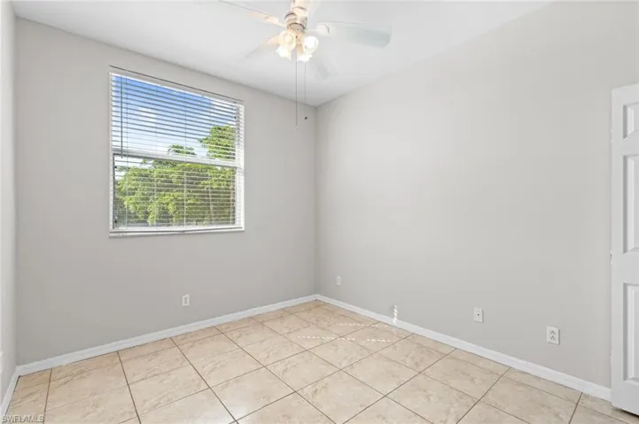 Unfurnished room with light tile patterned floors, baseboards, and ceiling fan
