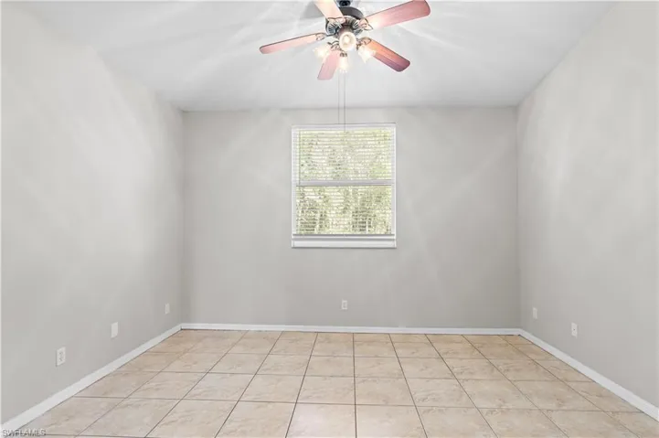 Empty room with light tile patterned floors, baseboards, and a ceiling fan