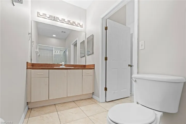 Full bathroom with a shower stall, tile patterned floors, vanity, and toilet