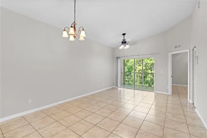 Empty room with visible vents, baseboards, ceiling fan with notable chandelier, high vaulted ceiling, and light tile patterned flooring