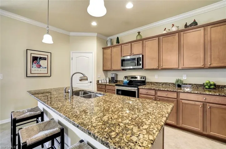 Kitchen featuring sink, a kitchen bar, ornamental molding, a kitchen island with sink, and stainless steel appliances