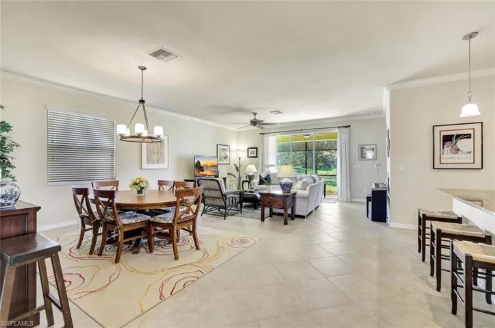 Tiled dining space featuring crown molding and ceiling fan with notable chandelier