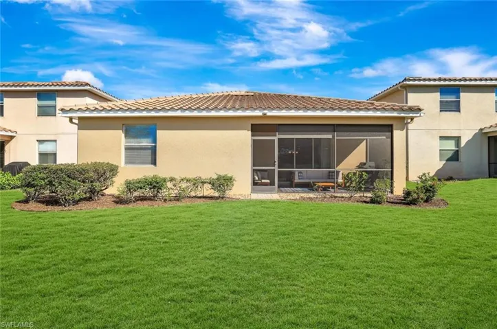 Rear view of property with a sunroom and a lawn