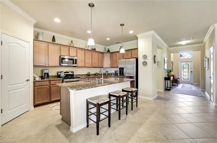 Kitchen featuring sink, appliances with stainless steel finishes, a kitchen island with sink, dark stone countertops, and a kitchen breakfast bar