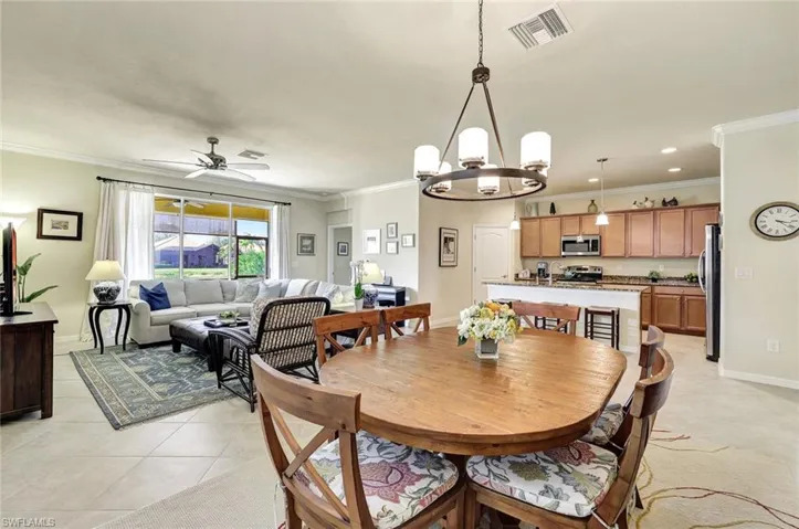 Dining space featuring crown molding, ceiling fan with notable chandelier, and light tile patterned floors